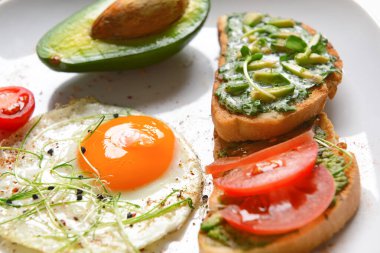 Lezzetli avokado sandviçleri ve tabakta kızarmış yumurta, yakın plan.