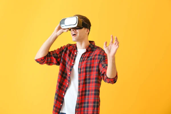 Junger Mann mit Virtual-Reality-Brille auf farbigem Hintergrund — Stockfoto