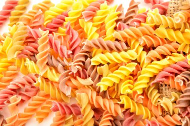 Beyaz arkaplanda pişmemiş lezzetli makarna, yakın plan.