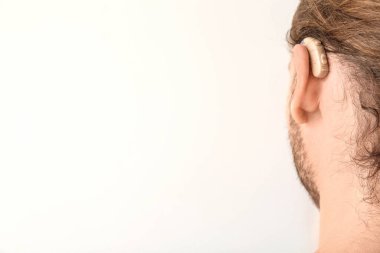 Beyaz arka plan üzerinde işitme cihazı ile genç adam
