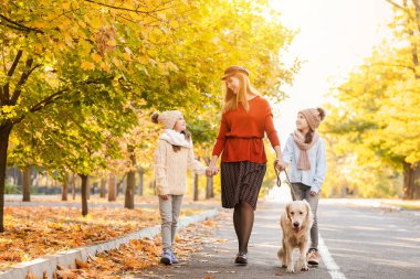 Sonbahar parkında köpekli mutlu bir aile.