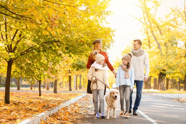 Keluarga bahagia dengan anjing berjalan di taman musim gugur — Stok Foto