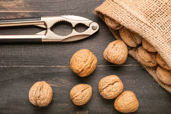 Мешок с вкусными грецкими орехами и орехами на деревянном фоне — стоковое фото