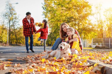 Sonbahar parkında köpeği dinlenen mutlu bir aile.