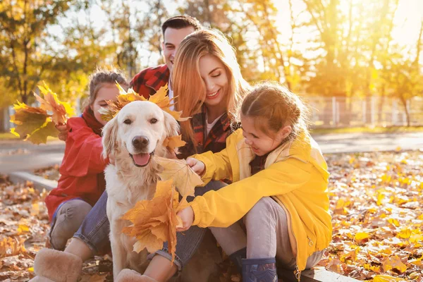 Familia feliz con perro descansando en el parque de otoño —  Fotos de Stock