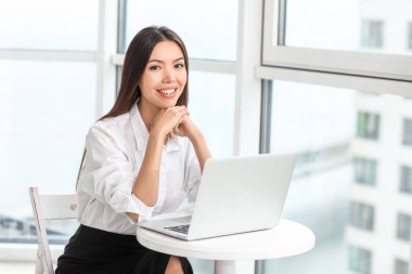 Ofisinde dizüstü bilgisayarı olan güzel Asyalı iş kadını.