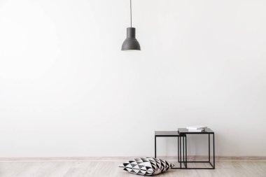 Yastıklı şık bir masa ve ışık duvarının yanında kitaplar.