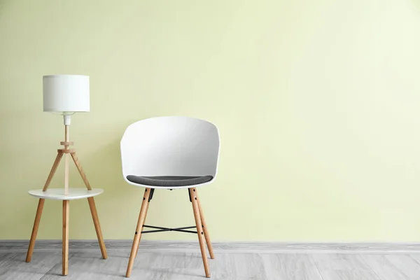 색 벽 근처에 탁자와 램프가 있는 멋진 의자 — 스톡 사진