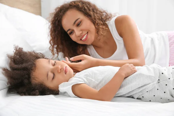 African-American mother with sleeping daughter lying on bed — Stock Photo, Image