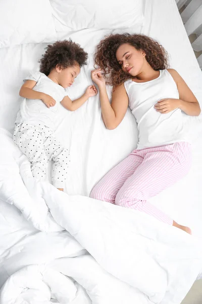 Niña afroamericana con madre durmiendo en la cama — Foto de Stock