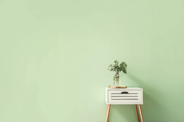 Stylish table with eucalyptus branches in vase on color background — Stock Photo, Image