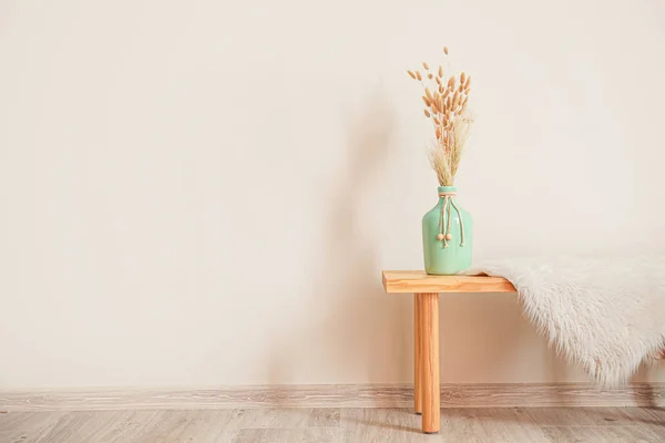 Beyaz duvarın yanında vazo ve ekoseli tahta masa. — Stok fotoğraf