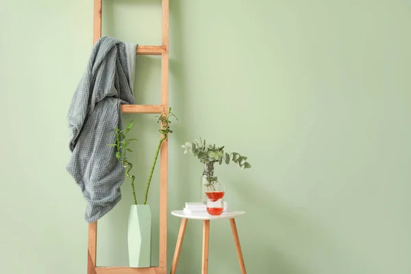 Стол с чашками чая и лестницы с клеткой на цветном фоне — стоковое фото