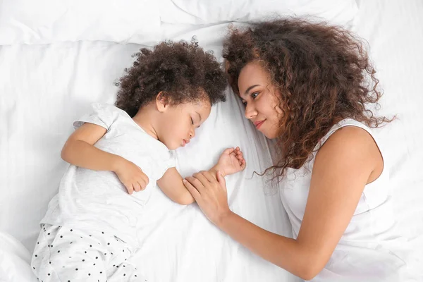 Madre afroamericana con hija dormida acostada en la cama — Foto de Stock