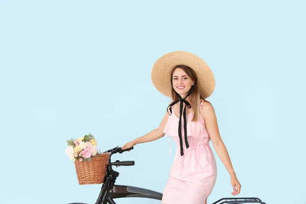 Mulher bonita com bicicleta e buquê de flores de cravo no fundo de cor — Fotografia de Stock