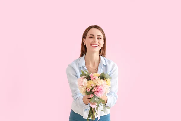 Vacker ung kvinna med bukett nejlika blommor på färg bakgrund — Stockfoto