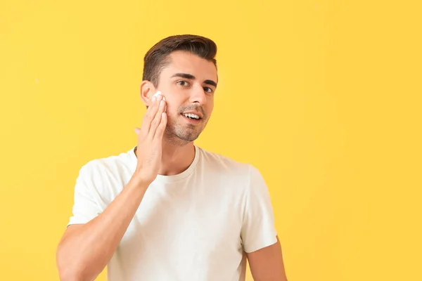 Handsome young man applying shaving foam against color background — Stock Photo, Image