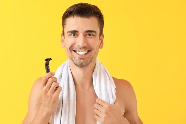 Handsome young man with razor on color background — Stock Photo, Image