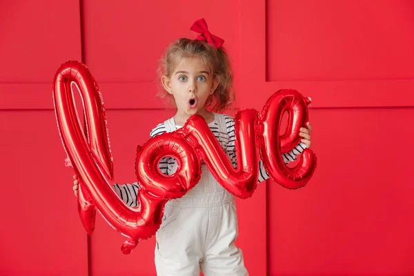 Carino bambina con palloncino d'aria in forma di parola AMORE su sfondo di colore. Festa di San Valentino — Foto Stock