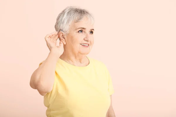 Senior kvinna med hörapparat på färg bakgrund — Stockfoto