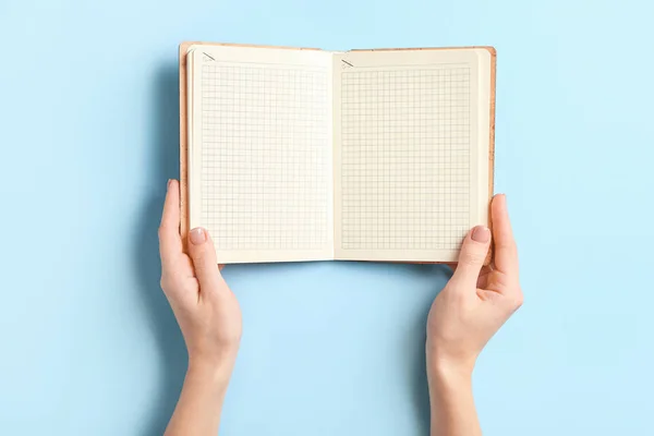 Kvinnliga händer med tom anteckningsbok på färg bakgrund — Stockfoto