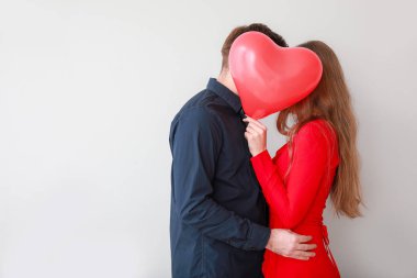 Arka planda kalp şeklinde balonları olan mutlu genç bir çift. Sevgililer Günü kutlaması