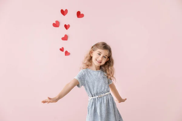 Niedliches kleines Mädchen auf farbigem Hintergrund mit Herzen. Valentinstag-Feier — Stockfoto
