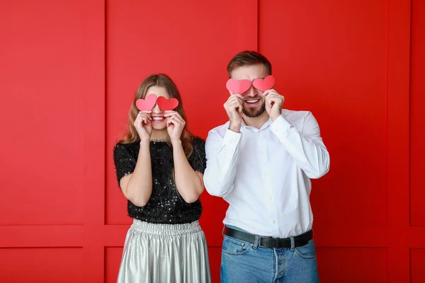 Happy young couple with red hearts on color background. Valentine's Day celebration — Stock Photo, Image