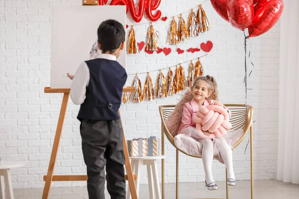 Pequeño niño pintando cuadro de linda chica en el interior. Celebración de San Valentín — Foto de Stock