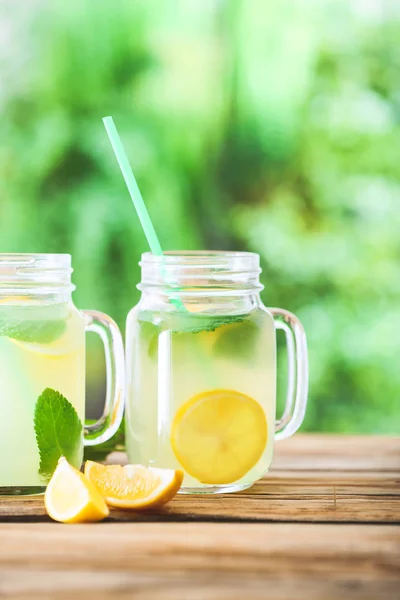 Mason jars of fresh lemonade on table outdoors