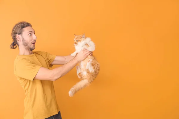 Shocked man with cute cat on color background — Stock Photo, Image