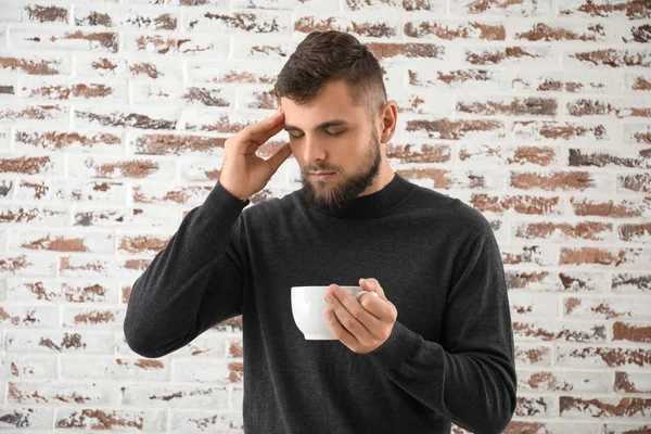 Porträtt av sjuk man med varmt te mot tegelvägg — Stockfoto