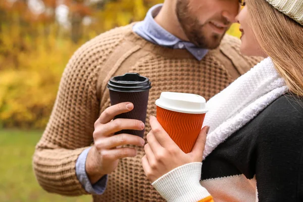 Liefdevol jong paar met kopjes koffie in het najaar park, close-up — Stockfoto