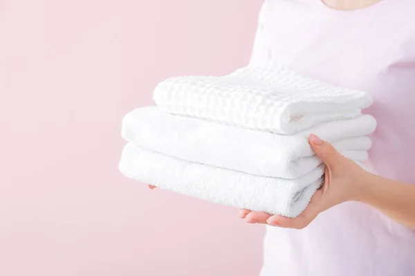 Mulher segurando toalhas limpas no fundo da cor — Fotografia de Stock