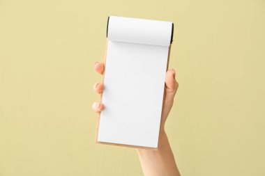 Renk arkaplanı üzerinde boş defter olan kadın el