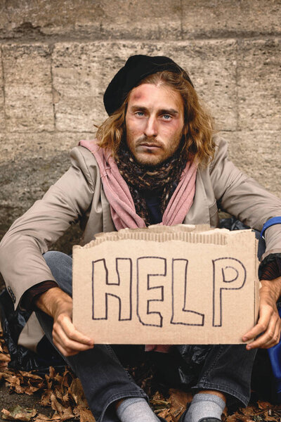 Poor homeless man holding cardboard with text HELP outdoors