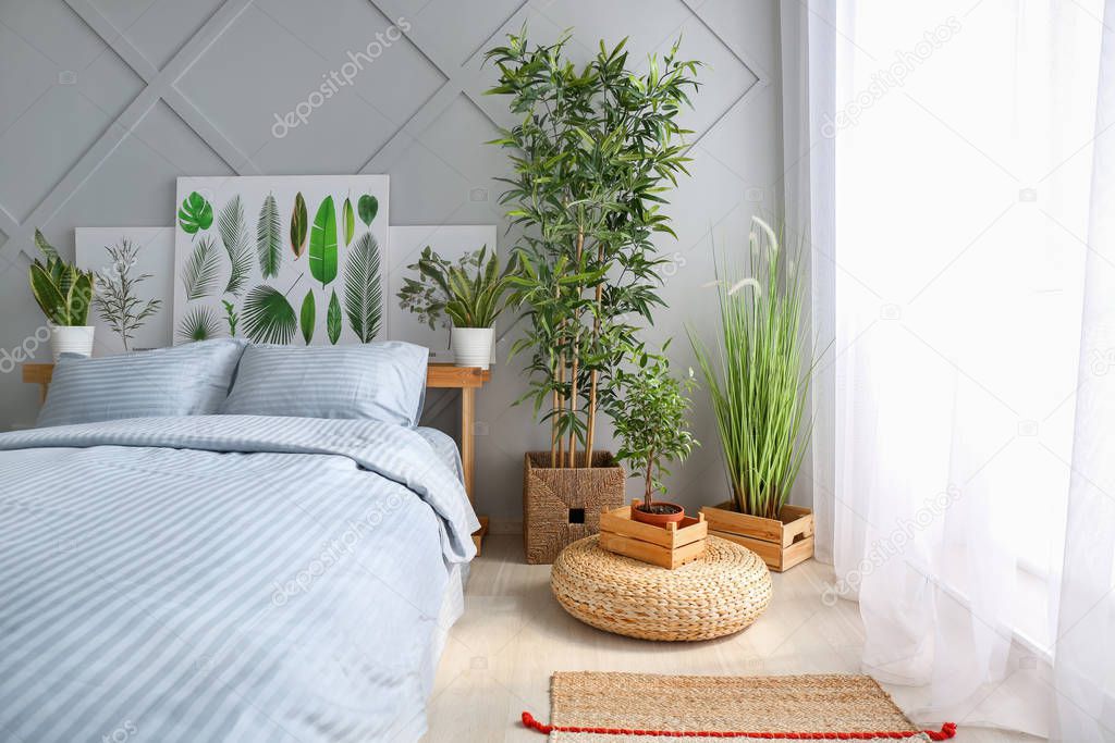 Big comfortable bed and plants in interior of room