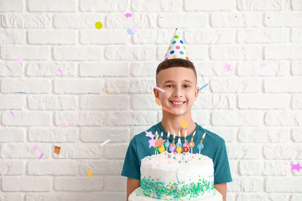 Menino com bolo de aniversário no fundo de tijolo branco — Fotografia de Stock