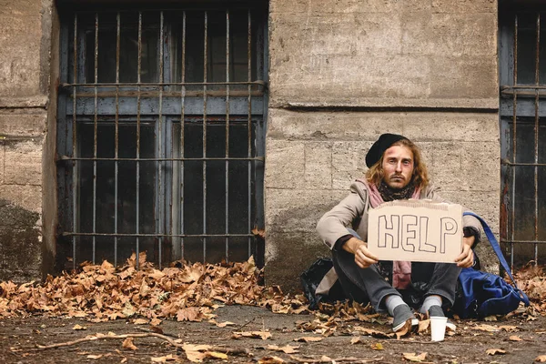 Pobre vagabundo sosteniendo cartón con texto AYUDA al aire libre —  Fotos de Stock