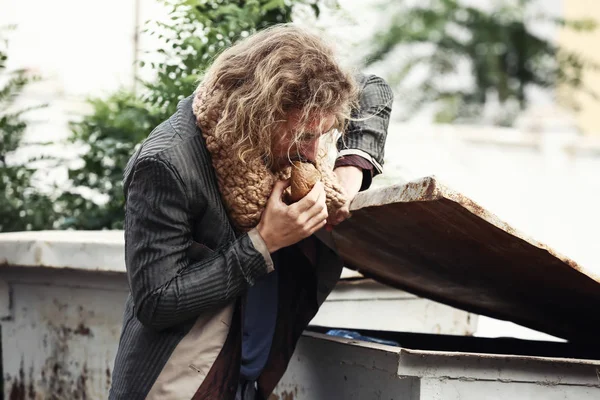Poor homeless man looking for food in garbage toter outdoors — Stock Photo, Image