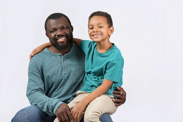 Retrato de homem afro-americano com seu filhinho em fundo claro — Fotografia de Stock