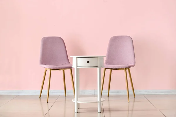 Table with chairs near color wall in room — Stock Photo, Image