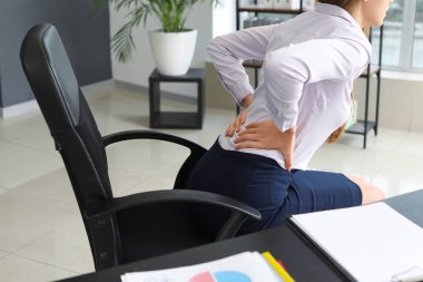 Ofiste sırt ağrısı çeken genç bir iş kadını.