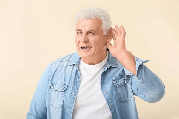 Mature man with hearing problem on light background — Stock Photo, Image