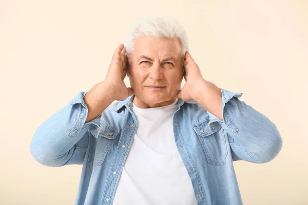 Hombre maduro con problemas de audición sobre fondo claro — Foto de Stock
