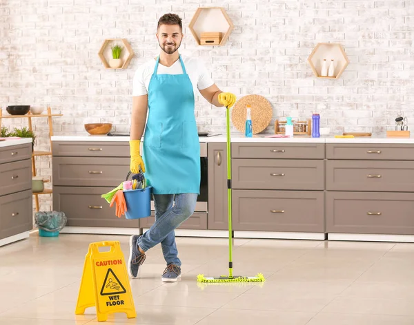 Conserje masculino con artículos de limpieza en la cocina —  Fotos de Stock