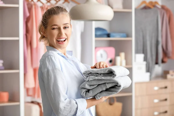 Vrouw met stapel schone kleren thuis — Stockfoto