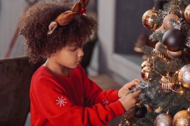 Evde Noel ağacı süsleyen küçük Afro-Amerikalı kız.