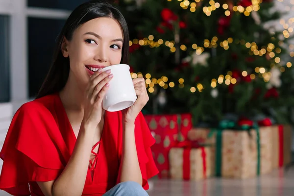 Belle femme asiatique boire du chocolat chaud à la maison la veille de Noël — Photo