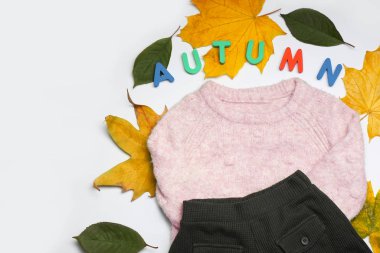 Beyaz arka planda yaprakları olan şık sonbahar çocuğu kıyafetleri.